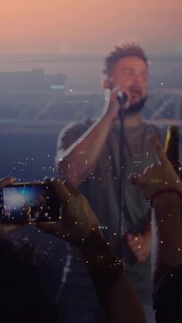 Vertical video: Fans holding phones filming causing glow while singer moving mic singing music