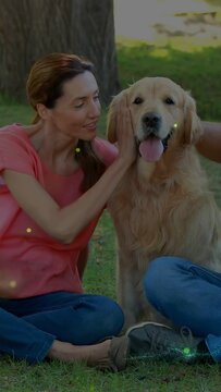 Vertical video: Woman stroking dog and activating sparkles while posing for device in pet care