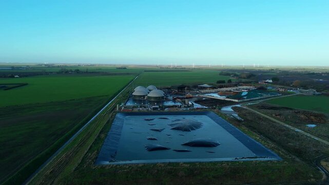Aerial view of a sustainable energy farm near Wisbech featuring anaerobic digesters and green gas domes for renewable power.