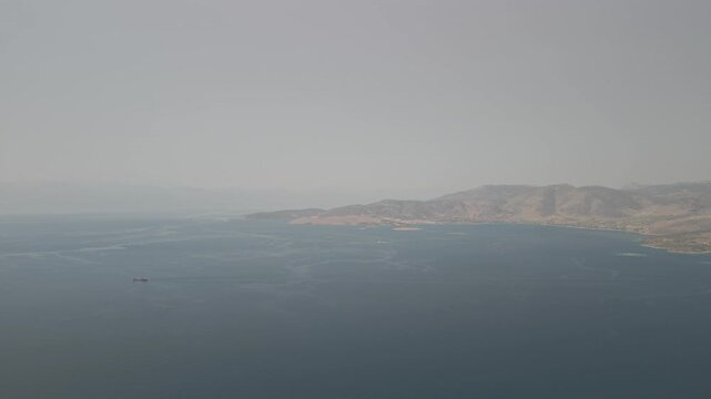 Aerial drone forward shot of a large ship sailing in calm waters near Lesbos island in the Aegean Sea, Greece on a sunny day.