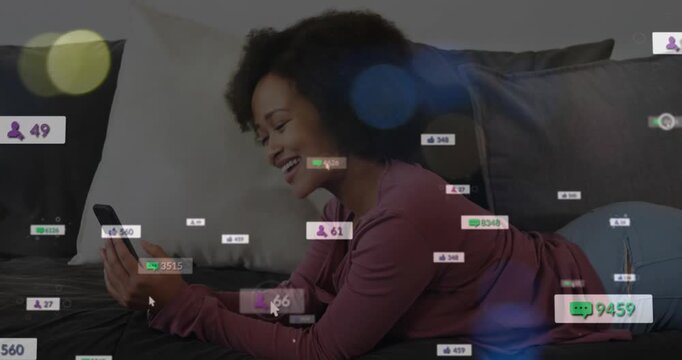 Animation of social media icons over african american woman having a videocall on the couch at home
