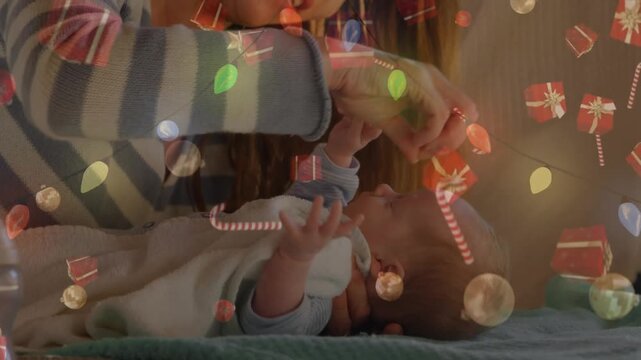 Animation of christmas decorations over caucasian mother holding baby