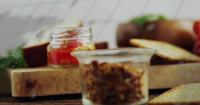 Wooden board being visualized in flat design, showing spice jar, crackers and red jam