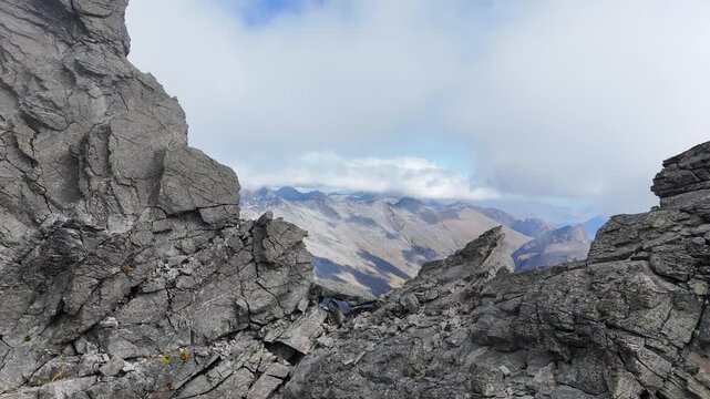 Proximity flight over rugged rocky mountain summit in cloud, nature