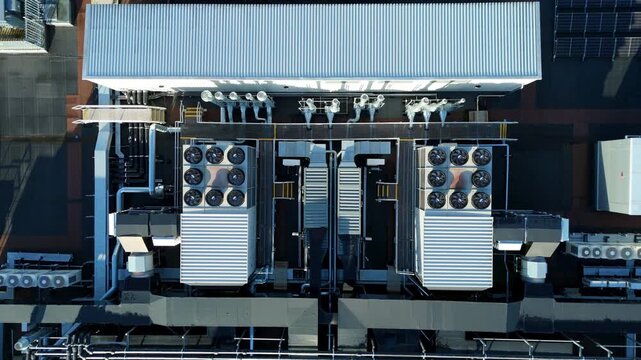 Aerial view of industrial HVAC units and cooling fans on a commercial rooftop, featuring symmetrical ventilation systems.