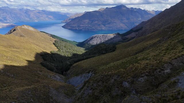 Aerial descends mountain drainage from saddle of Ben Lomond in NZ