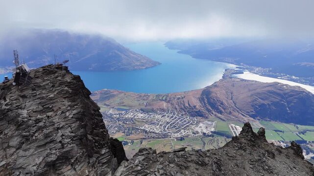 Aerial orbits telecom tower on rugged mtn top at Queenstown New Zealand