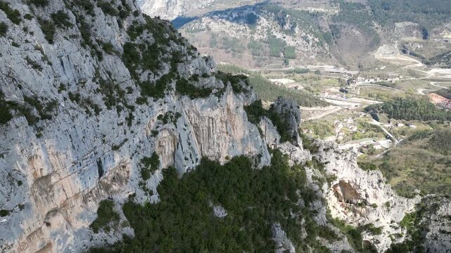 Aerial drone footage over Frasassi Gorge, Italy: rocky cliffs, green vegetation and dramatic natural landscape. Ideal for travel, nature and geological projects.