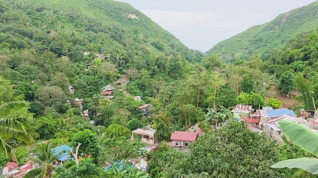 Hillside community with houses among dense tropical forest in Busay, Cebu City, Central Visayas, Philippines, overlooking Buhisan watershed within Central Cebu Protected Landscape, panning