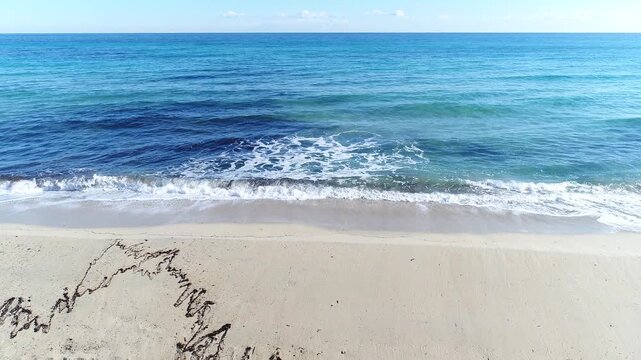 Camber Sands with gentle waves rolling onto sandy beach with clear blue water and soft foam creating calm coastal scene in natural outdoor setting