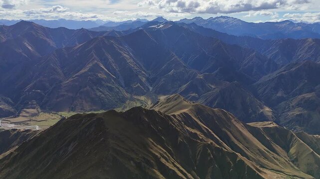 Rugged green mountain range flyover, river in valley far below cloud