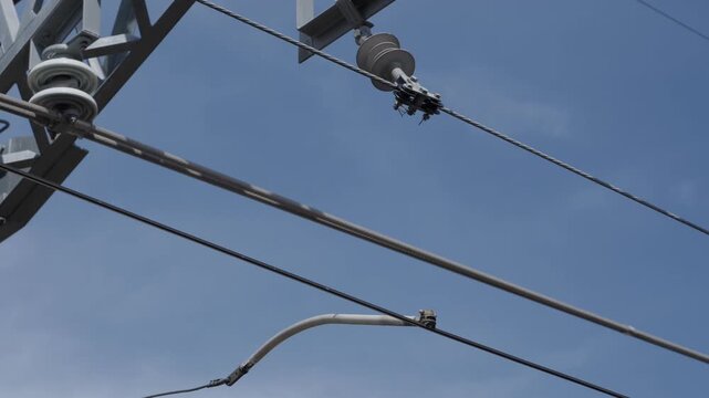 Low angle view of steel electricity transmission pylon with ceramic insulators and high voltage cables against clear blue sky