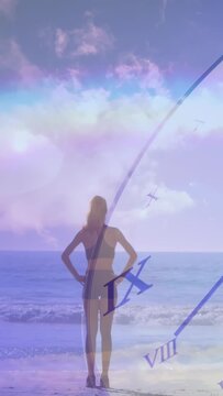 Vertical video: Woman stepping to sea, causing clock hand advancing and rainbow pulsing for health