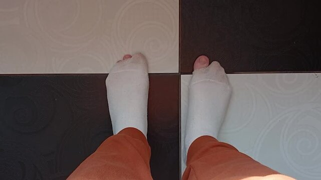 Stock video of feet in torn socks standing on black and white floor - poverty