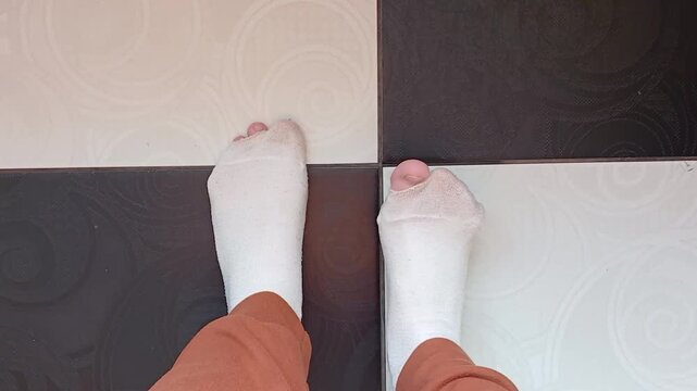 Stock video of feet in torn socks standing on black and white floor and wiggling their toes - poverty