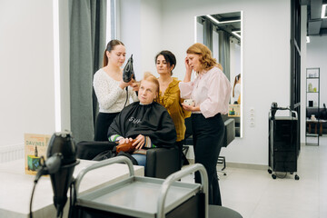 Fototapeta premium Four talented stylists work together in a chic salon, giving a client a fresh look. The atmosphere is buzzing with energy, creativity, and the smell of hair products.