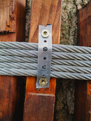 A close-up of a metal cable attached to a tree. Children's rope park