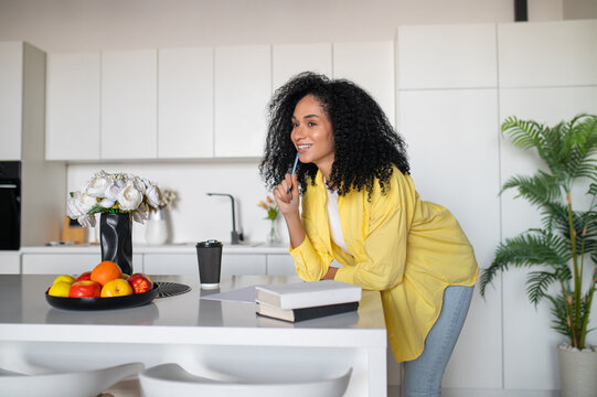 Beautiful young woman sitting at the table and looking inspired and excited