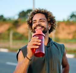 Obraz premium Portrait of a happy man holding a bottle of water refreshment posing and smiling after exercicing outdoors. Athlete and fitness and healhty living concept