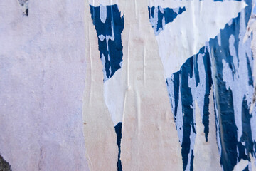 Billboard with old posters. White, blue ripped torn posters texture background in city street