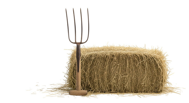 Rustic pitchfork resting against a square bale of golden straw hay on a dark background capturing a rural farming scene