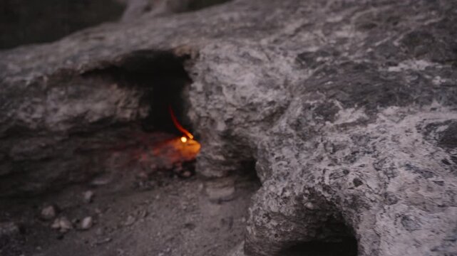 Natural Eternal Flame Burning from a Crack in a Rocky Surface at the Chimaera in Turkey, Ignited by Underground Gas Emissions, Surrounded by Dark Soil and Stone, Captured in Low Light