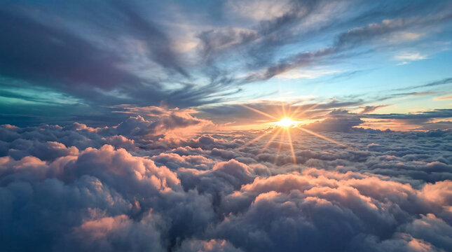 A serene aerial view of fluffy white clouds illuminated by a bright sun at sunrise or sunset with a blue sky and scattered wispy clouds