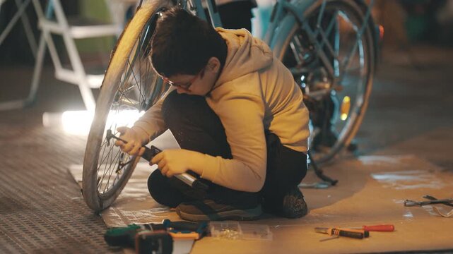 Young boy inflating bicycle tire with pump