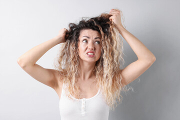 Fototapeta premium Unhappy woman with tangled hair on light grey background,