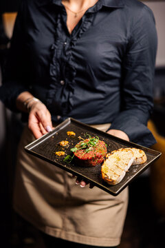 Beef tartare with bread slices on elegant black serving board
Gourmet steak tartare with herbs and modern fine dining presentation
Close up of raw beef tartare with toast and artistic plating