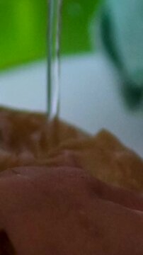 Series shows a woman preparing kombucha in a rural Ukrainian home. She rinses the tea mushroom, cleans jars, pours fermented drink into bottles, highlighting traditional lifestyle and health benefits.