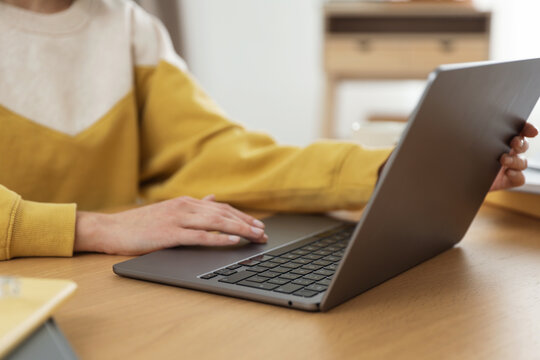 Woman working with laptop at wooden table indoors, closeup