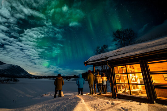 Northern lights over cabin and tourists in Tromso, Norway