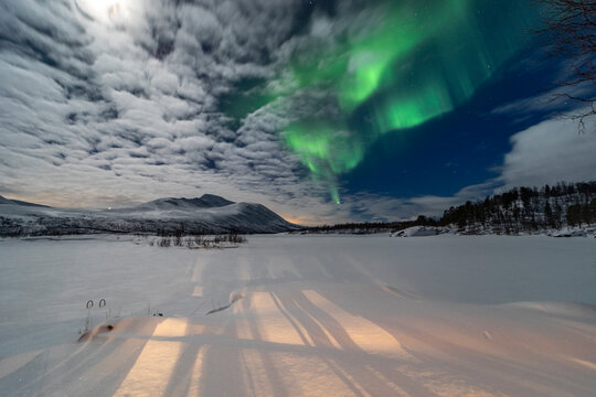 Aurora over snowy lake and mountains near Tromso, Norway