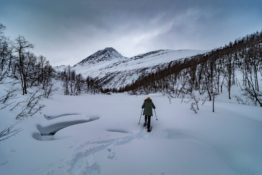 Winter hiker crossing snowy valley near Tromso, Norway