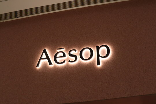 Backlit Aesop brand logo on a textured brown store wall in a shopping mall on March 30 2026 in Chengdu, China.