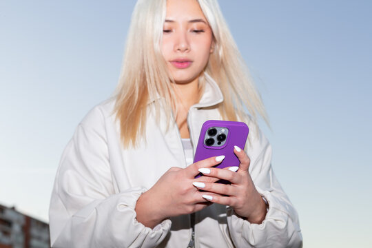 Urban flash Gen Z girl using smartphone outdoors at dusk