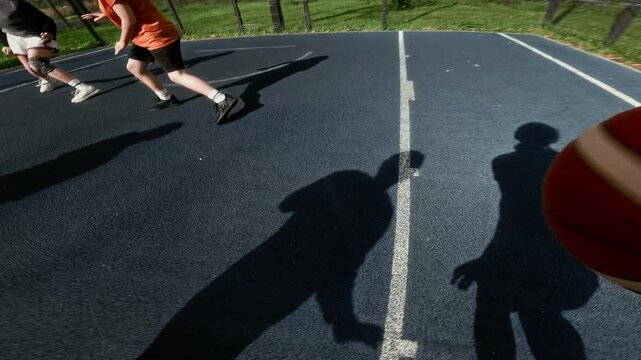 Action camera POV shot of unrecognizable teenage girl playing basketball outdoors dribbling ball across public court and shooting for hoop, copy space