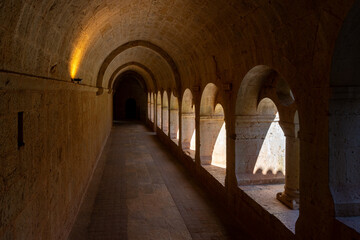 Le Thoronet Abbey cloister corridor, Provence-Alpes-Côte d’Azur, France : Romanesque arches and perspective in monastery interior