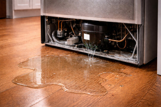 Broken refrigerator compressor with oil leak on floor at back side
