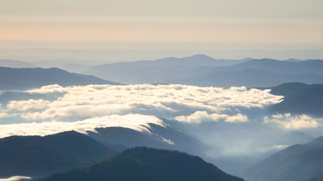 Temperature inversion view from Ceahlău Massif in Romania showing dense sea of fog filling mountain valleys beneath soft morning light.