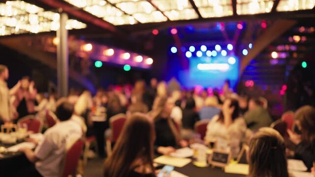 Attendees at fundraising dinner focus on stage while servers attend to guests