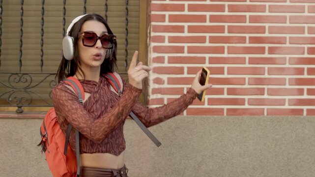 Happy young woman dancing listening to music on headphones outdoors