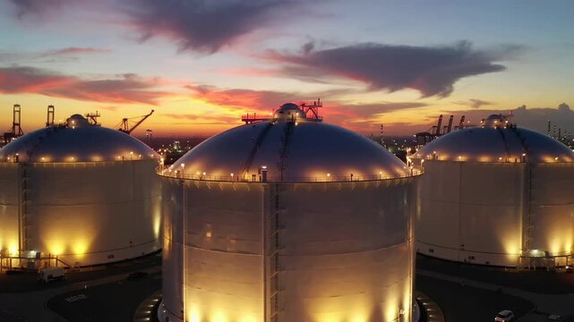 Liquefied natural gas storage tanks at industrial port during sunset aerial view