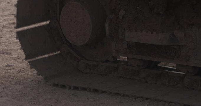 Caterpillar tank tread wheels driving slowly over dusty earth construction military vehicle