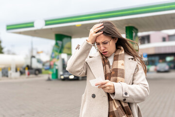Fuel inflation concept woman shocked by gas receipt © Maksym