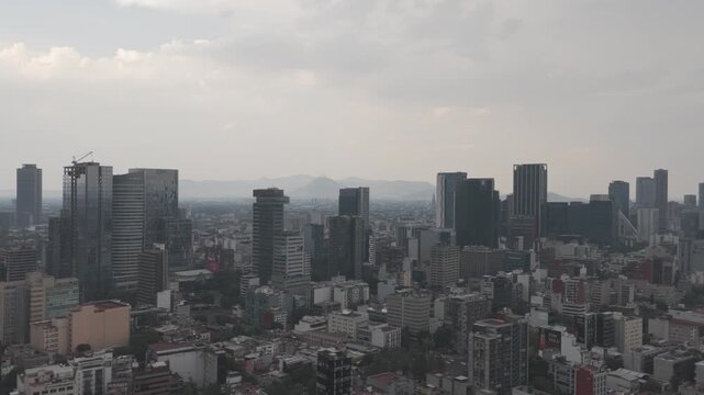 Aerial drone flying sideways over Colonia Roma with Paseo de la Reforma skyline and hazy sky in M&eacute;xico City. Shot in D-Log M