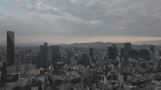 Aerial panoramic view of the Paseo de la Reforma skyline, drone flies left to right during the sunset.