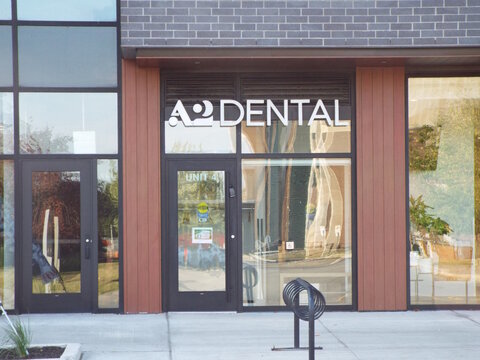 Ottawa, Ontario, Canada &ndash; July 25, 2025: A modern "A2 Dental clinic" entrance featuring glass doors, minimalist white signage, a black bike rack, and a brick exterior facade at 770 Brookfield Rd Unit 