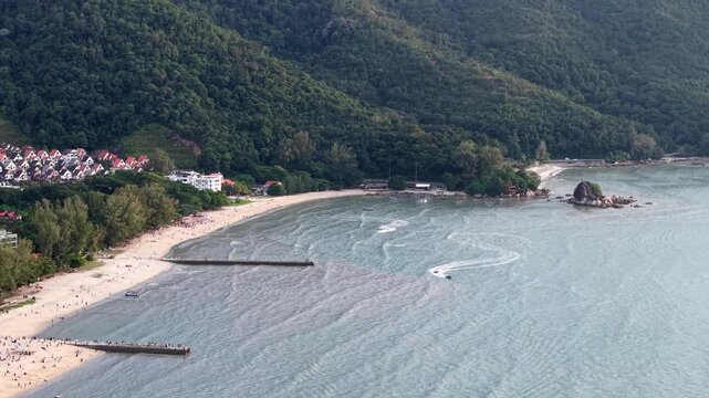 Beautiful beach with a rocky shoreline and a small island in the distance. The water is calm and the sky is cloudy